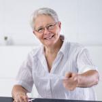 Une femme souriante assise à une table tend un document pour maximiser son impact fiscal